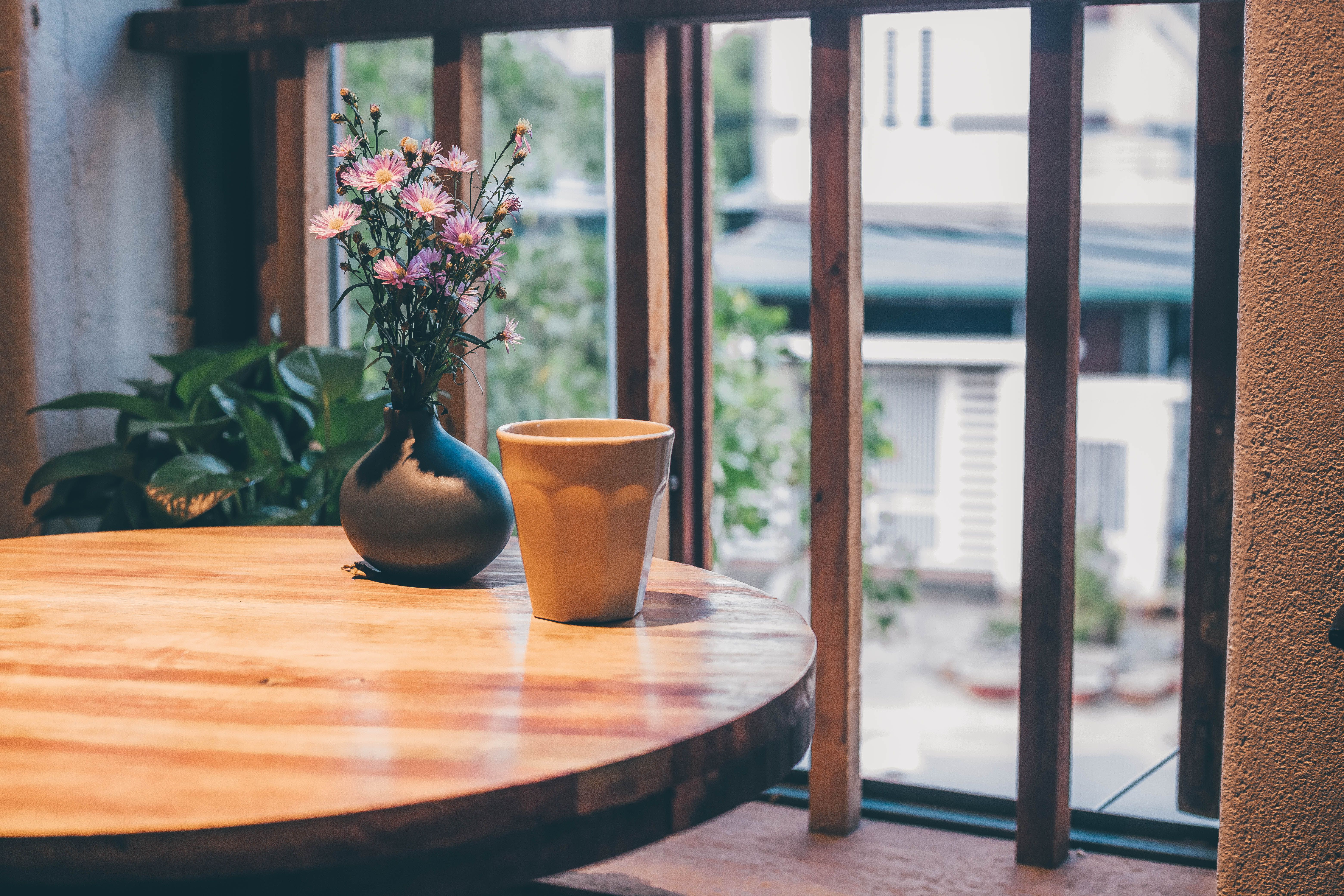 Peaceful setting with ceramic cup and flowers on a wooden table indoors.