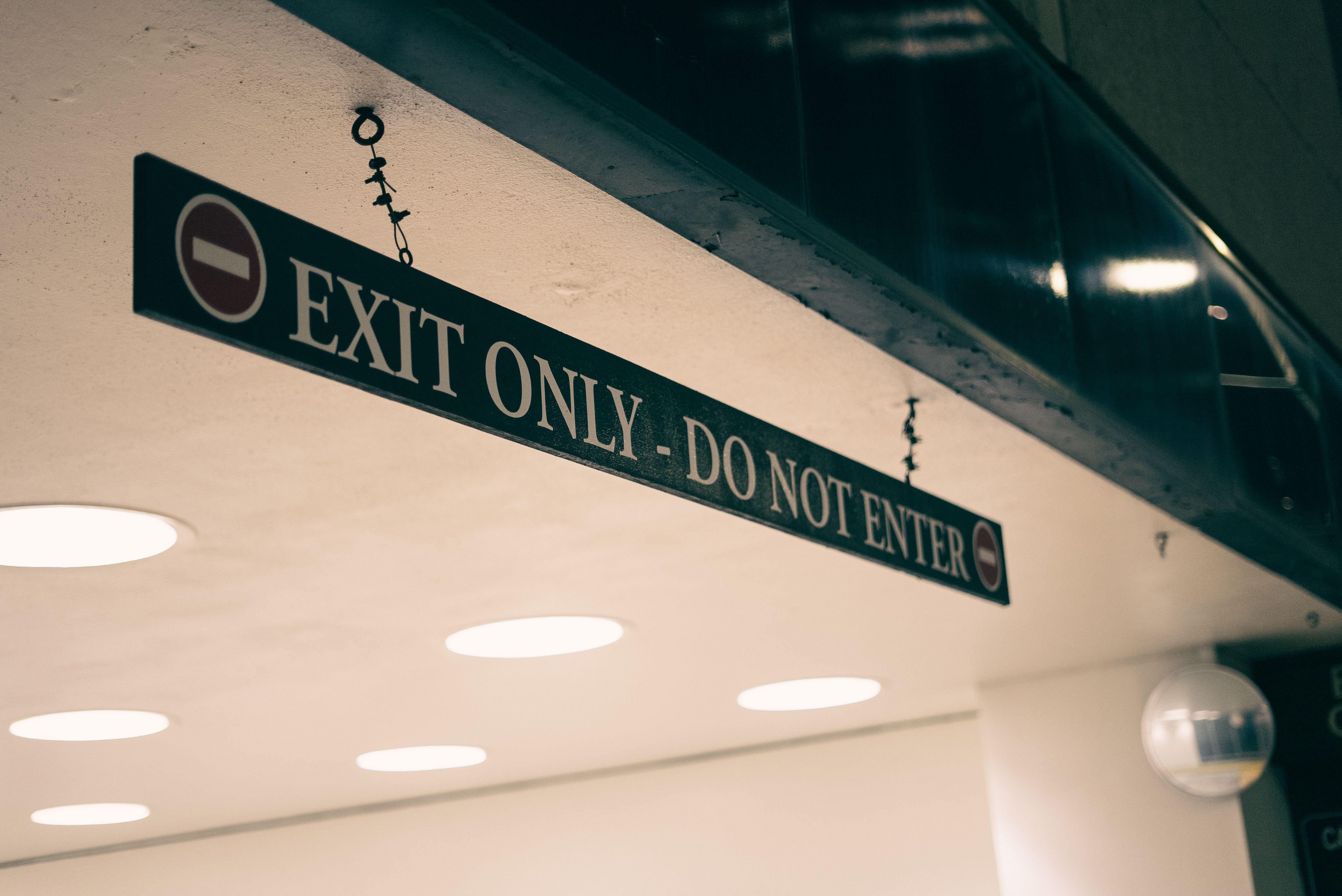 Close-up of an 'Exit Only' and 'Do Not Enter' sign in an indoor urban setting.