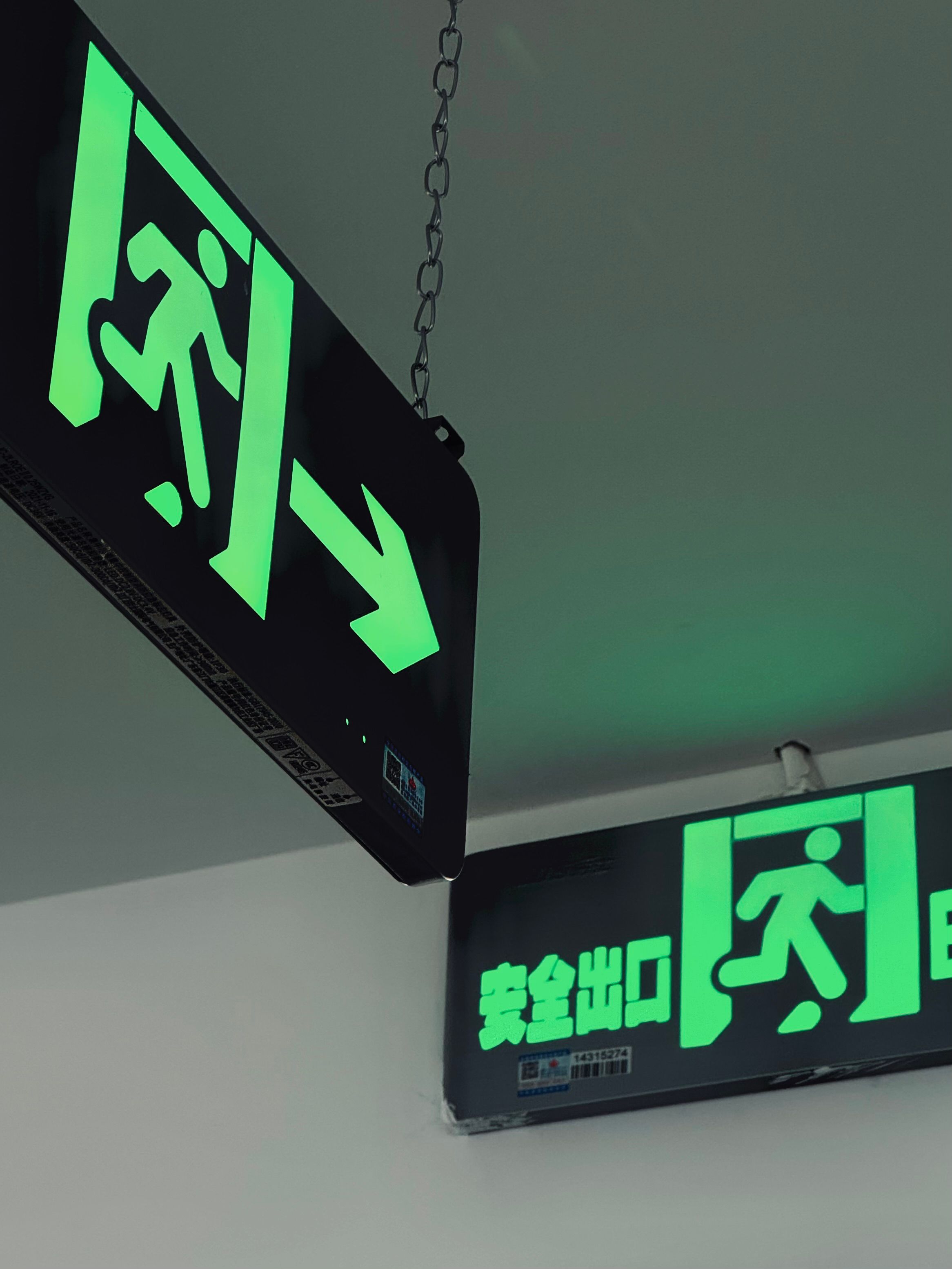 Bright green emergency exit signs with arrow direction in indoor Tianjin location.