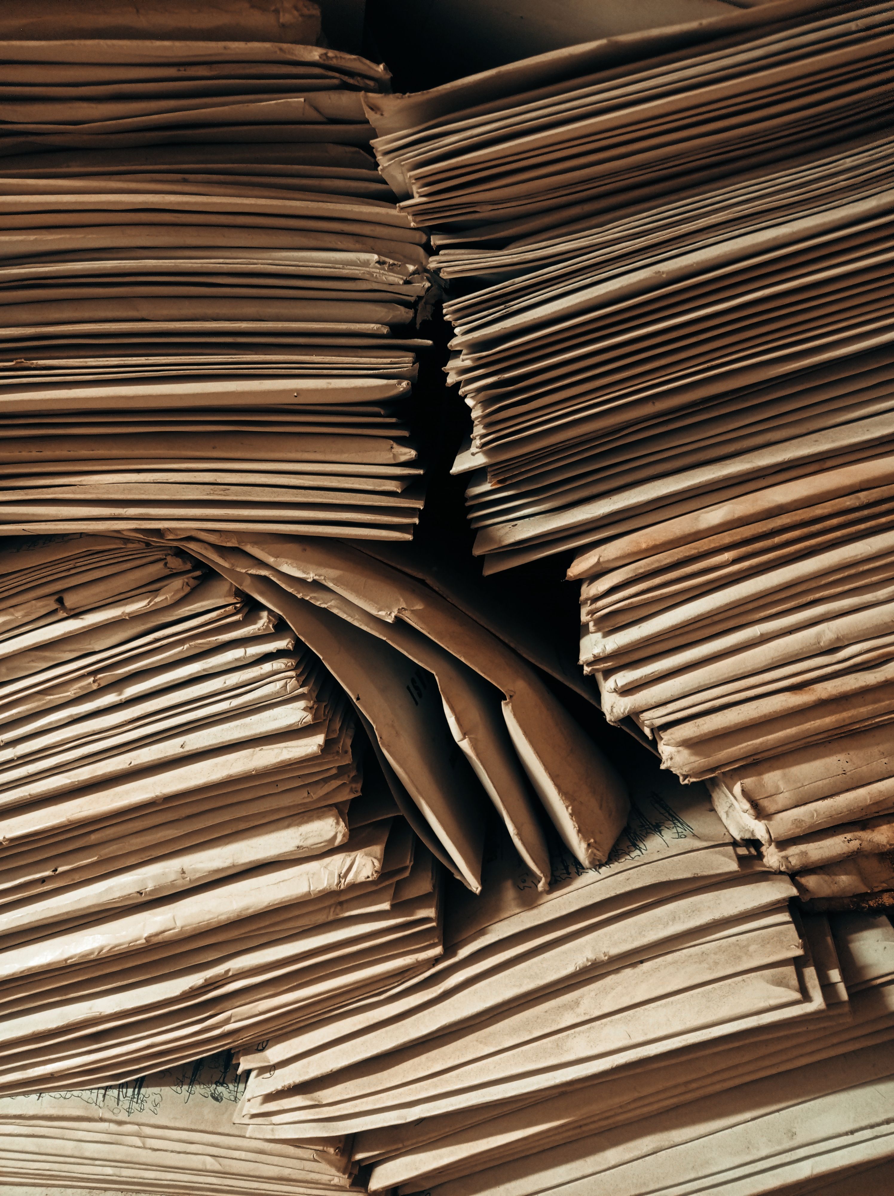 Piles of aged brown paper envelopes stacked closely, highlighting vintage archival storage.