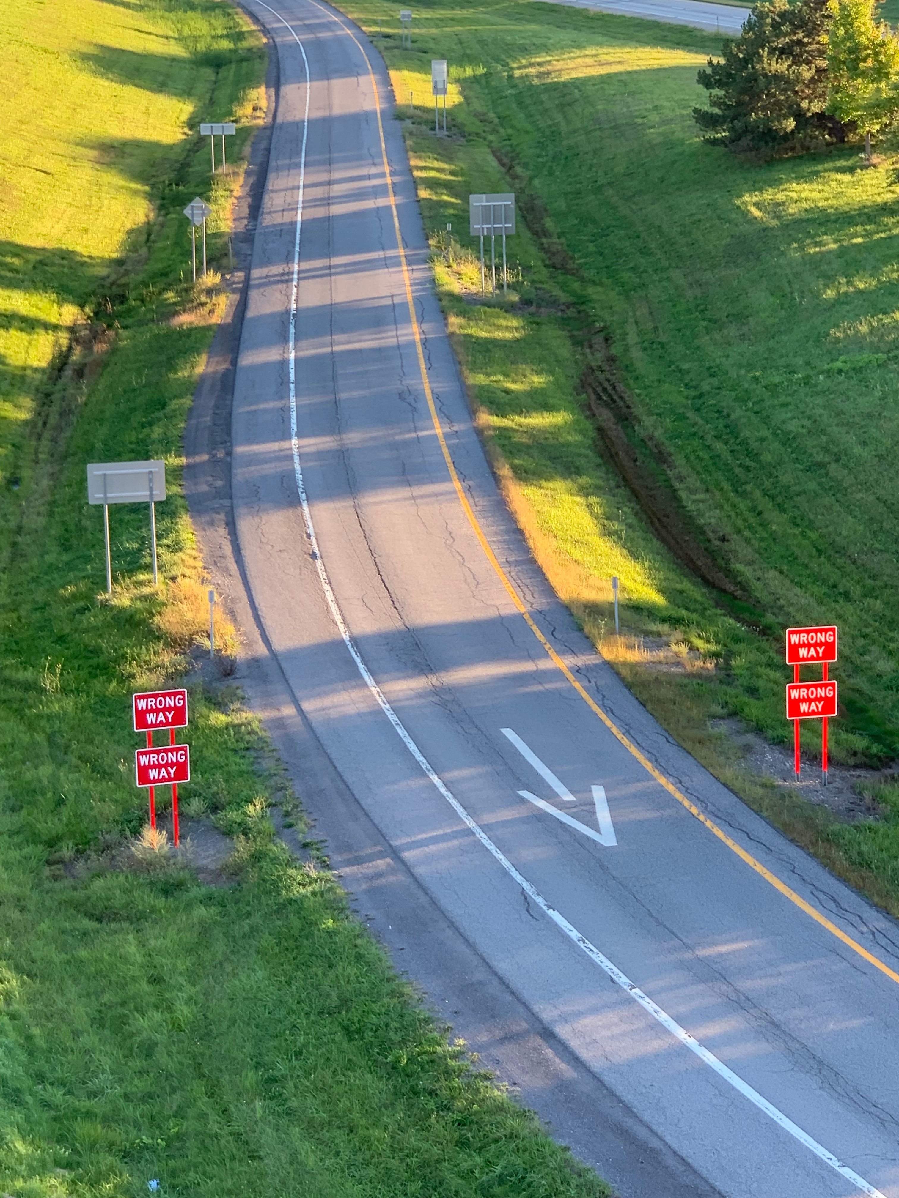 Aerial view highlighting a wrong way road sign on a highway exit ramp in Lakeville, New York.