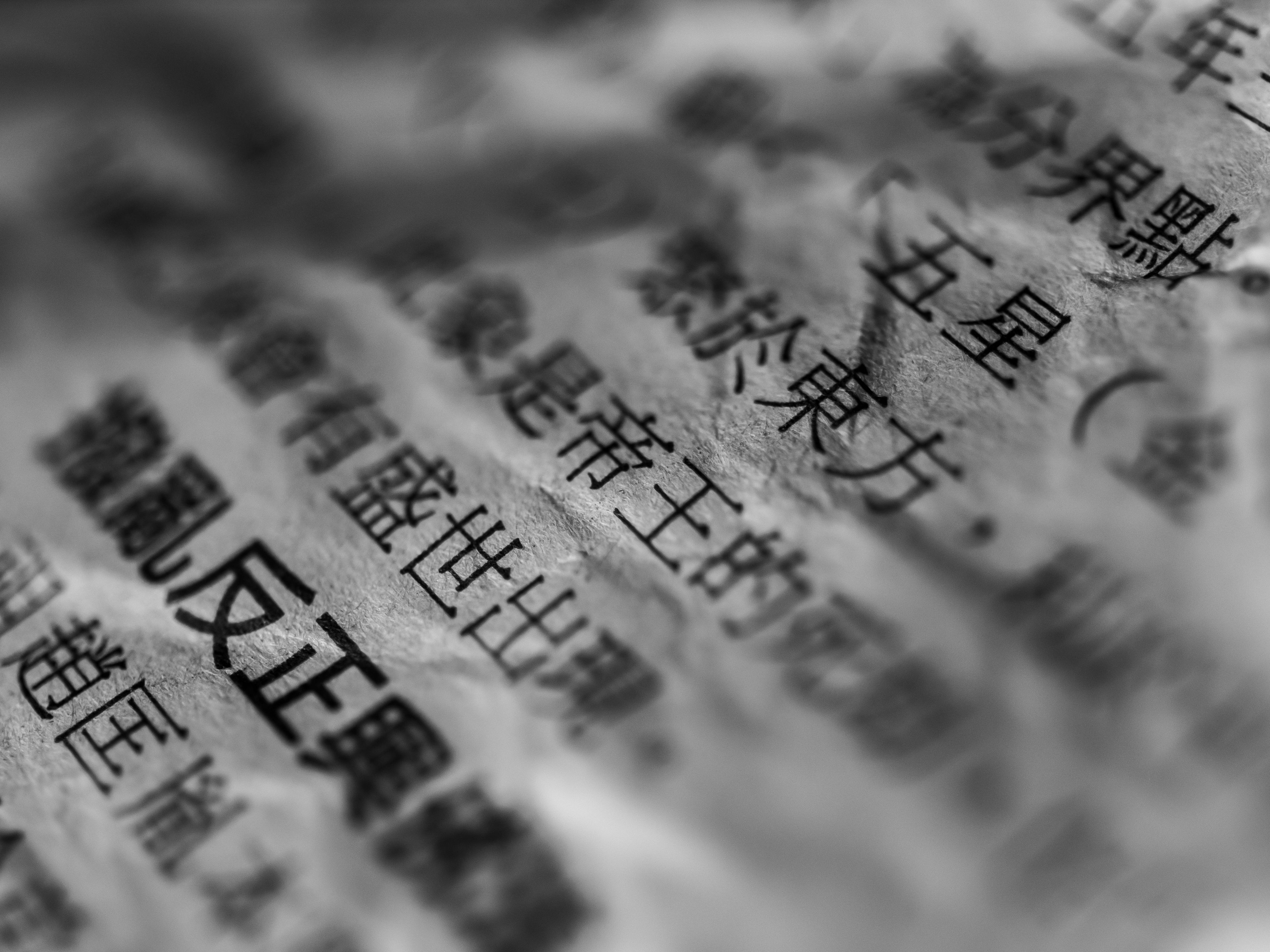 Artistic close-up of Chinese text on crumpled paper with selective focus and blur.